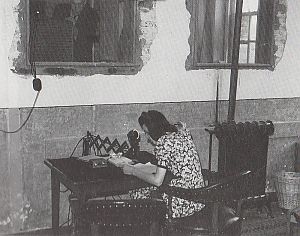 <p>Omroepster Syb Arends verzorgt onder weinig riante omstandigheden een uitzending van de OPMC, 1945. &ndash; Foto: RTV Noord</p>
