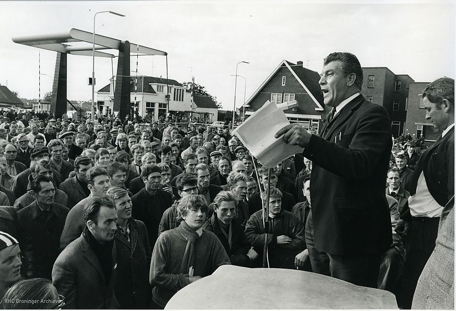 <p>Fré Meis spreekt de stakers in de strokarton toe bij de Wedderklap in Oude Pekela. – Foto: collectie Groninger Archieven</p>
