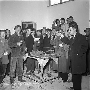 Leden van VERA en bouwvakkers heffen het glas tijdens de verbouwing van hun sociëteit in 1956. - Foto: Fotobedrijf Piet Boonstra, www.beeldbankgroningen.nl (2248-7506)