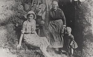 <p>Fennechien Wiekens (staand) met een onbekende vrouw en kind bij haar plaggenhut. - Foto: collectie Groninger Archieven</p>
