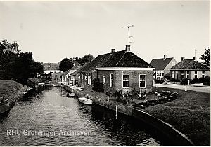 <p>Het pand aan het water deed in de oorlog dienst als noodhospitaal. De brug over het maar was opgeblazen. Een platte schuit deed dienst als noodbrug. Losdorp, 1973.&nbsp;<em>Foto M.A. Douma, Groninger Archieven</em></p>
