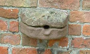 De piscina van de kerk van Garmerwolde heeft aan de buitenkant een waterspuwer in de vorm van een kattenhoofd.